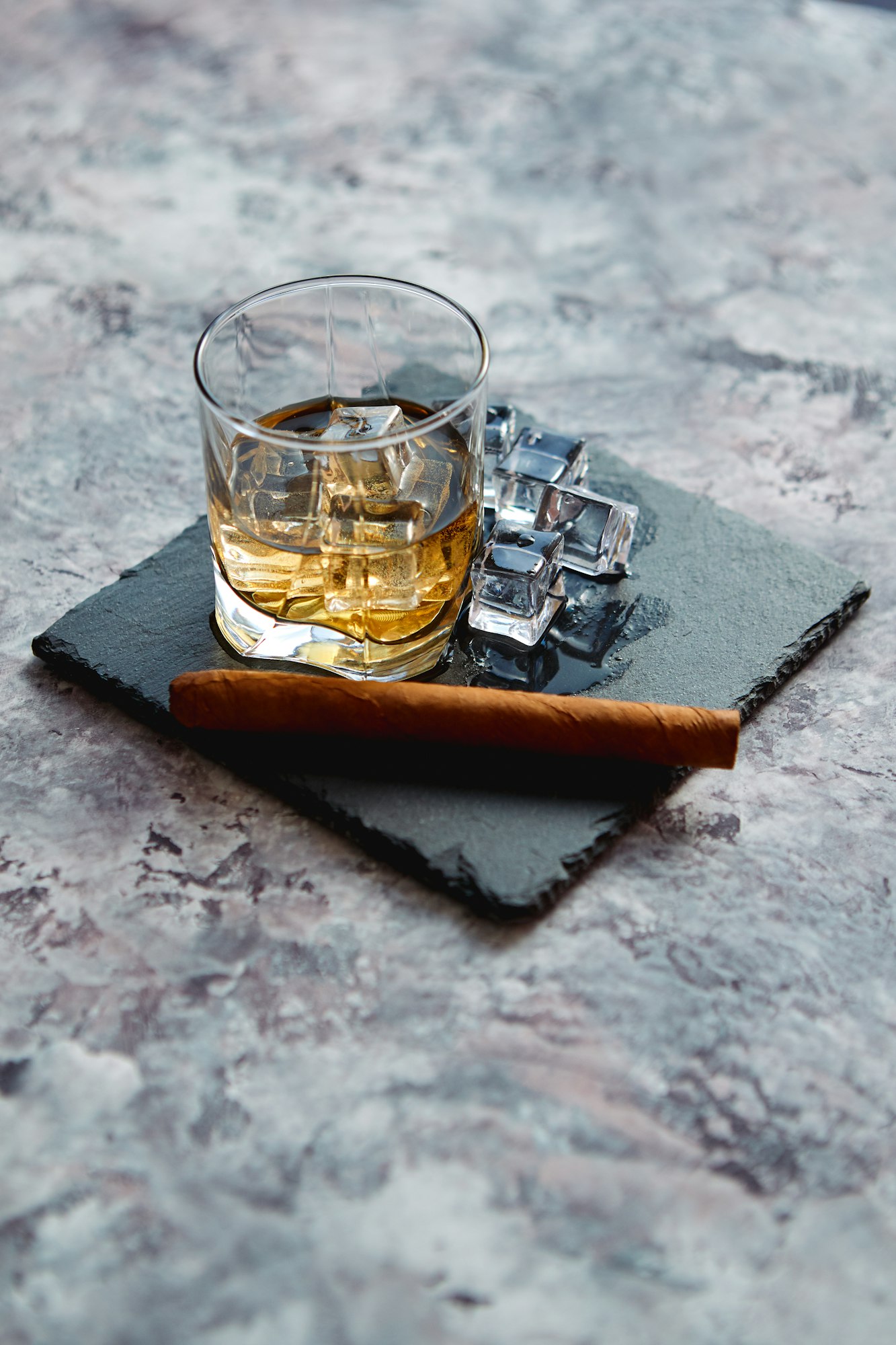 Glass of whiskey with ice cubes and cigar